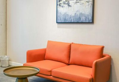 Brightly colored orange sofa and abstract wall art in a modern lounge area.