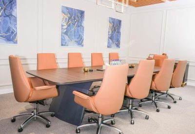 Professional meeting room with a large wood table, tan leather chairs, and blue abstract paintings.