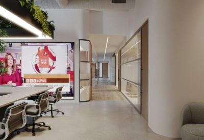 Modern workspace hallway featuring glass-walled offices and ergonomic office chairs.