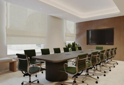 Professional boardroom with a long dark wood table, green chairs, and a large wall-mounted screen.