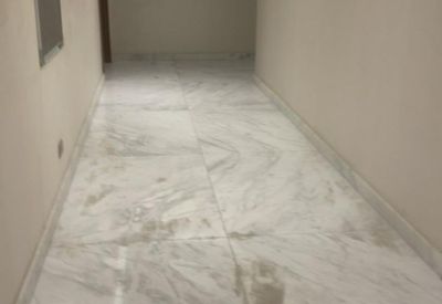 Modern corridor with polished white marble tile flooring and recessed ceiling lighting.