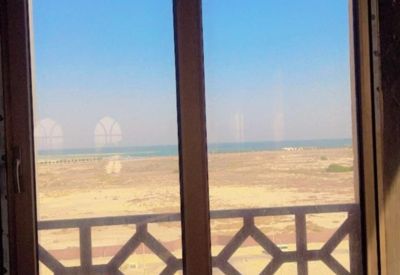 Window view of the coastline through a brown frame with geometric lattice patterns.