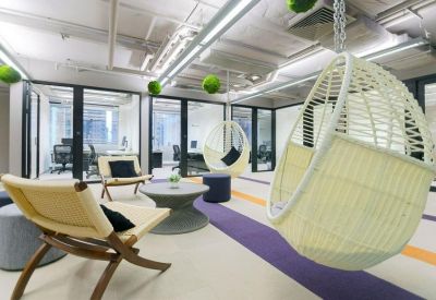 Lounge area featuring hanging wicker chairs, modern seating, and floor-to-ceiling windows.