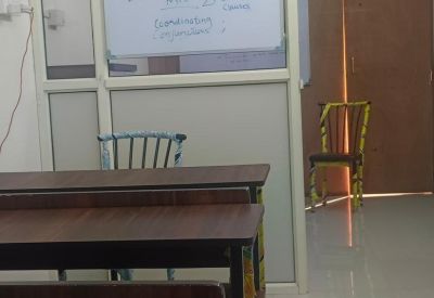 Small classroom featuring a whiteboard with notes and several student benches.