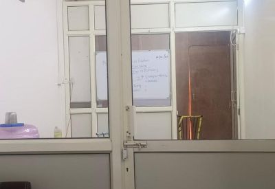 Internal view through a glass partition showing a private office space with a desk.