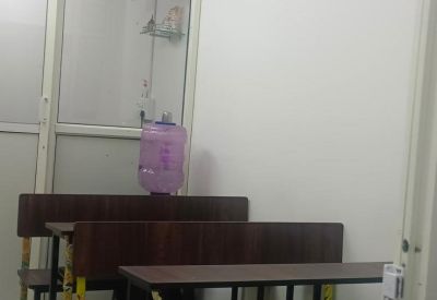 Classroom setting featuring several rows of dark wood student benches and desks.