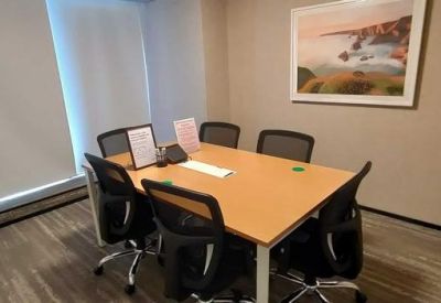 Private meeting room with a wooden table, mesh chairs, and scenic landscape artwork.