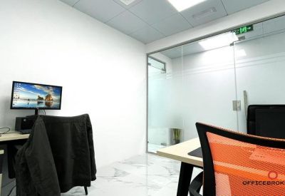 Bright office space with a glass partition wall and an orange mesh chair.