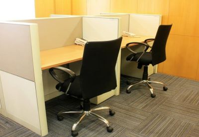 Private office cubicle with a wooden desk and black rolling chair.