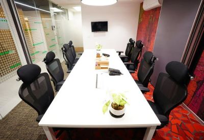 Modern conference room with a long white table and black ergonomic chairs.
