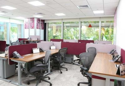 Modern open-plan office with rows of desks and ergonomic chairs.