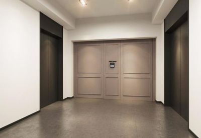 Modern elevator lobby with neutral-toned paneled walls and dark flooring.