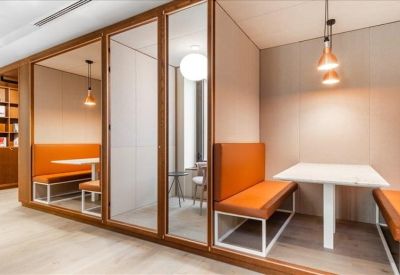 Private meeting booths with orange cushioned seating and glass partitions.