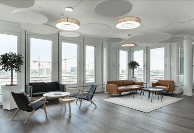 Spacious lounge with leather sofas, large windows, and modern circular ceiling light fixtures.