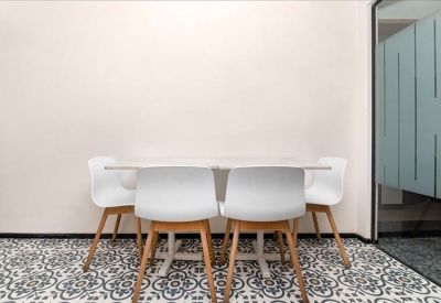 Communal dining area with white chairs and patterned tile flooring.