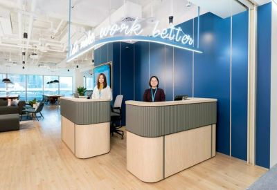 Modern reception desk with a blue feature wall and neon work better signage.
