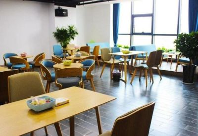 Bright communal lounge and cafe area with colorful blue and gold chairs and potted plants.