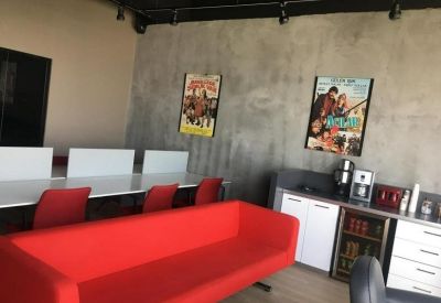 Breakout space featuring a long red sofa and a coffee station against a concrete-style wall.