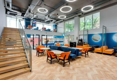 Modern lobby area with orange and blue seating, wooden staircase, and circular pendant lights.