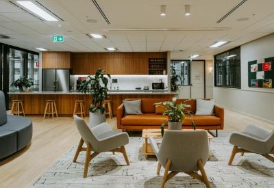 Communal breakout space with a kitchen, leather sofa, and modern armchairs.