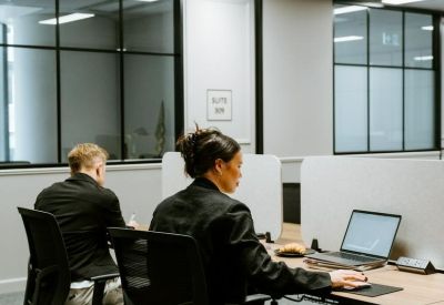 Coworking space with people working at desks separated by privacy screens.