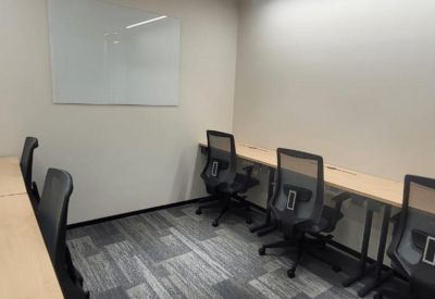 Compact meeting room with long wooden desks and a whiteboard.
