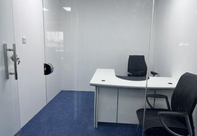Bright private office suite with a white L-shaped desk and ergonomic black chairs.