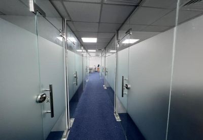 Symmetrical hallway featuring frosted glass office partitions and blue carpeting.