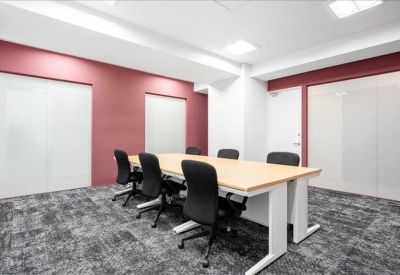 Spacious meeting room featuring a long wooden table, black chairs, and a red feature wall.