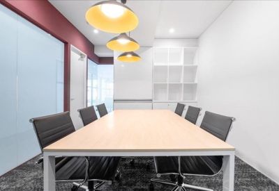 Professional boardroom with a light wood table and elegant grey mesh chairs.