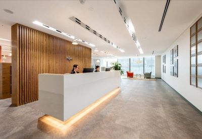 Modern white reception desk with warm under-lighting and vertical wood slat partition.