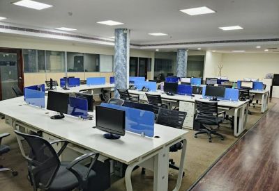 Large open-plan office with rows of desks, blue privacy screens, and wood-look flooring.