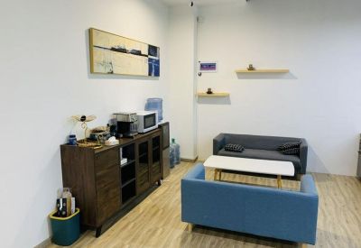 Communal breakroom with a wooden sideboard, coffee station, and two small sofas facing a coffee table.