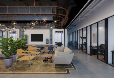 Bright breakout lounge with sofas, yellow armchairs, and indoor plants next to glass-walled offices.