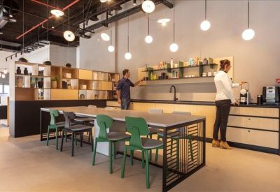 Vibrant communal kitchen and dining area with green chairs and globe pendant lights.