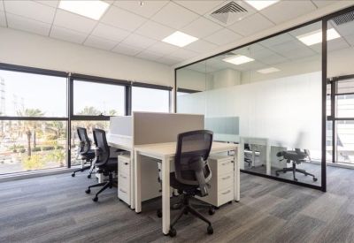Bright open-plan office space with white desks and mesh chairs.