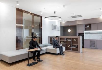Communal lounge area with comfortable grey seating and a library wall.