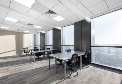 Bright open-plan office with multiple workstations and floor-to-ceiling windows.
