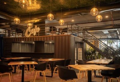 Industrial-style cafe with container-style walls, warm globe lighting, and wooden tables.