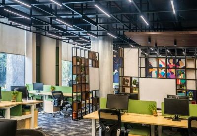 Open-plan office with lime green dividers, black mesh chairs, and a dark geometric ceiling.