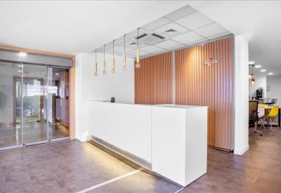 Bright reception area featuring a white desk, wood-slatted walls, and glass doors.