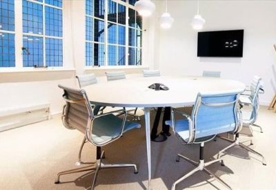 Minimalist meeting room with a round white table, blue chairs, and large grid windows.