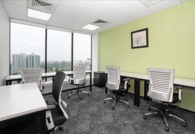 Bright office space with white desks and mesh chairs against a pale green feature wall.