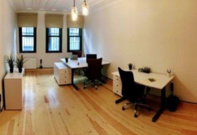 Private office featuring wooden floors and two white desks with black ergonomic chairs.