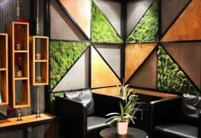 Lounge area with moss-covered geometric wall panels and leather armchairs.