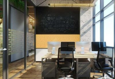 Open-plan workspace with multiple monitors, wooden desks, and a large blackboard wall.