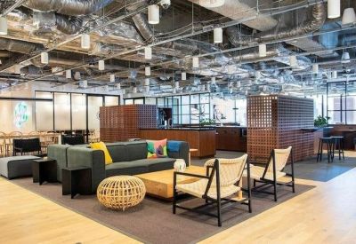 Expansive communal breakout area featuring a large grey sofa and industrial ceilings.
