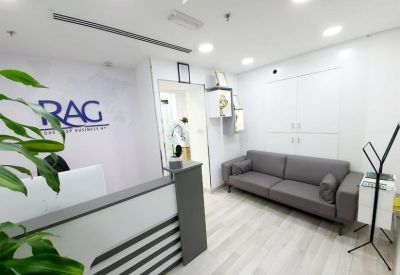 Modern reception desk with company branding and grey sofa.