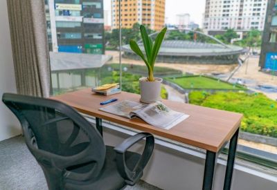 Single workstation desk by a window with a city view and a small potted plant.
