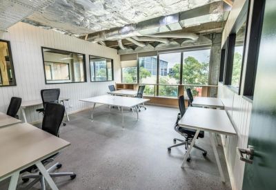 Bright, white private office suite with multiple workstations and large windows.
